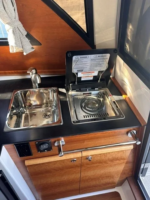 Slide: The Image of Compact kitchenette with stainless steel sink and gas stove, surrounded by wood paneling and windows. - 45