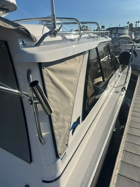 Slide: The Image of A modern boat with white side panels and windows, docked at a marina. - 27