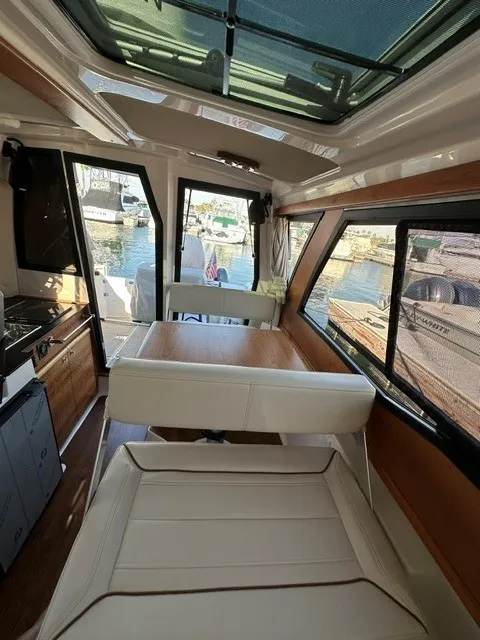 Slide: The Image of Interior of the Cutwater C-248 Coupe with table and bench seating, surrounded by windows overlooking the harbor. - 37