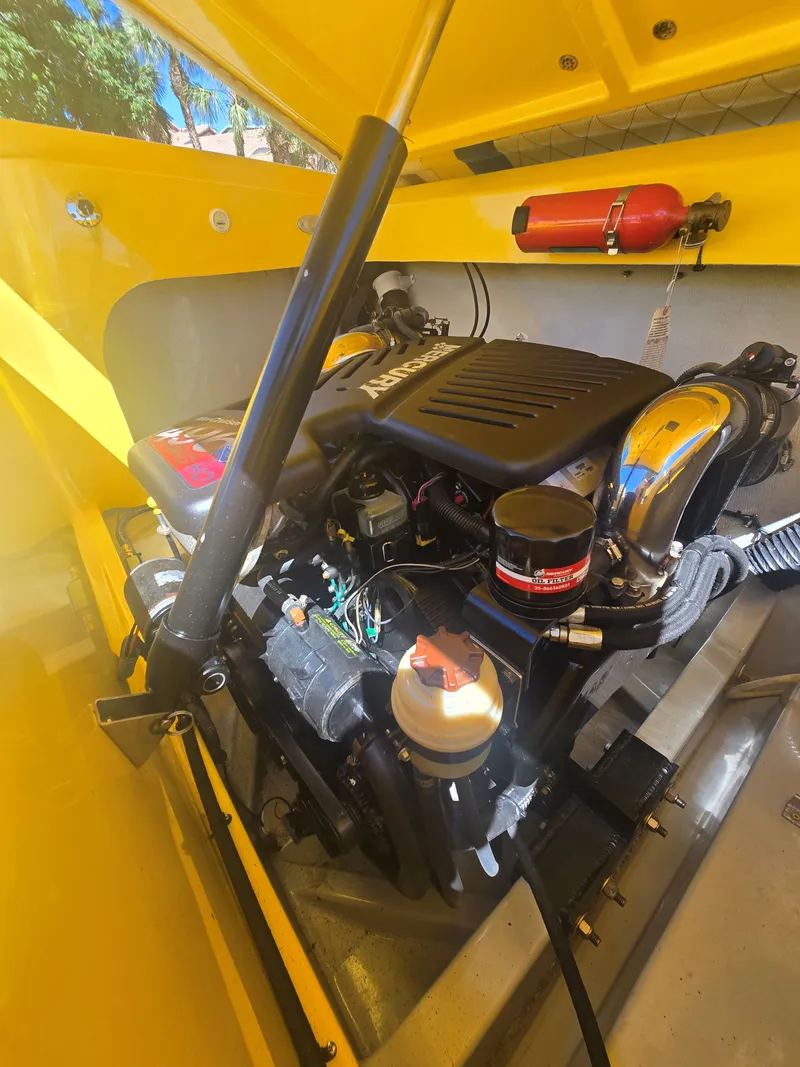 Slide: The Image of The engine compartment of a yellow 2007 Baja 26 Outlaw with a powerful engine and fire extinguisher. - 16