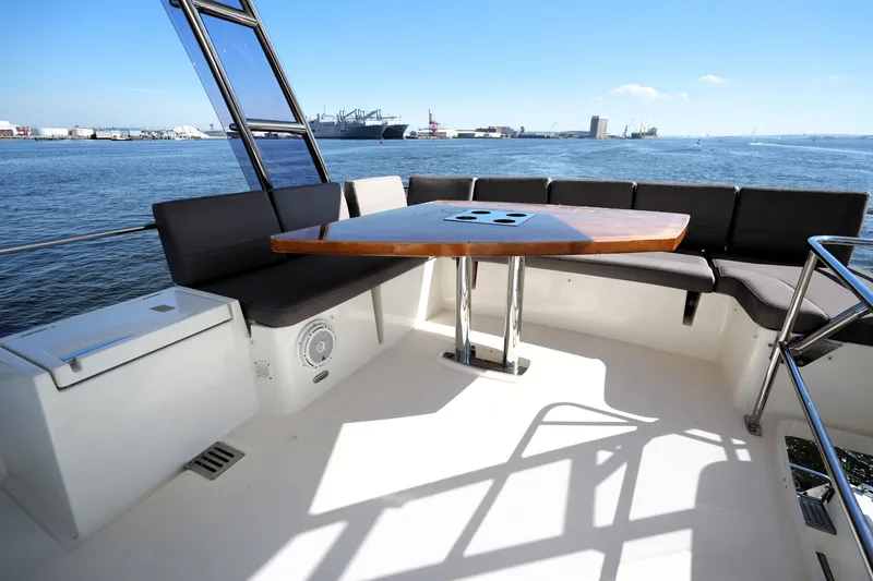 Slide: The Image of Flybridge seating area on a 2016 Prestige 550 yacht, overlooking a scenic harbor view. - 27