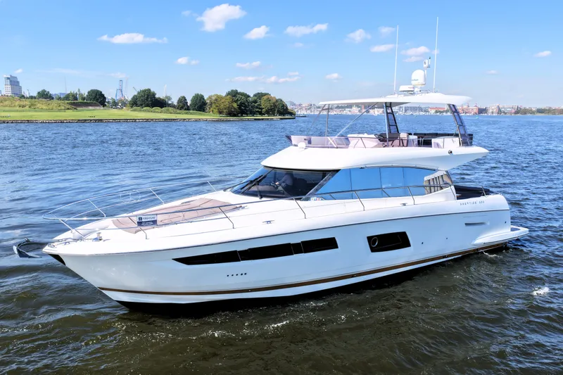 Slide: The Image of Luxury 2016 Prestige 550 yacht cruising on a scenic river under a clear blue sky. - 5