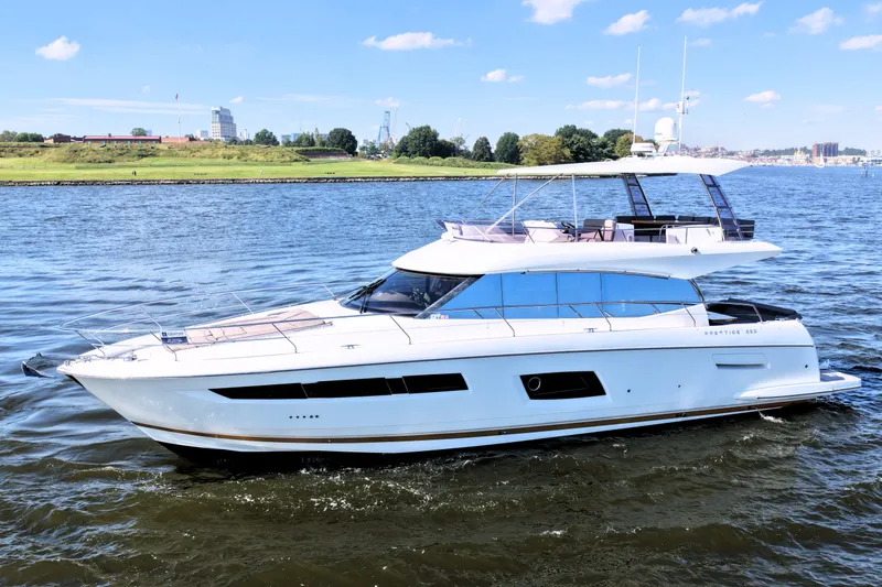 Slide: The Image of Luxury 2016 Prestige 550 yacht cruising on a scenic river under a clear blue sky. - 7