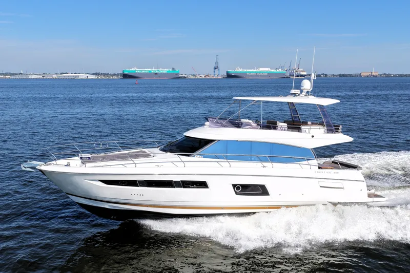 Slide: The Image of 2016 Prestige 550 yacht cruising on open water with cargo ships in the background. - 8