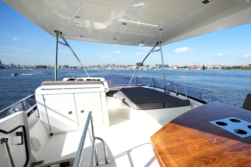Slide: The Image of Luxurious 2016 Prestige 550 yacht deck with seating, table, and scenic waterfront view. - 25
