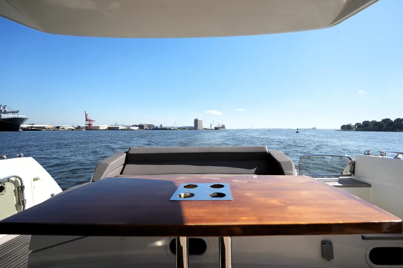Slide: The Image of Luxury 2016 Prestige 550 yacht with scenic waterfront view and wooden table. - 18
