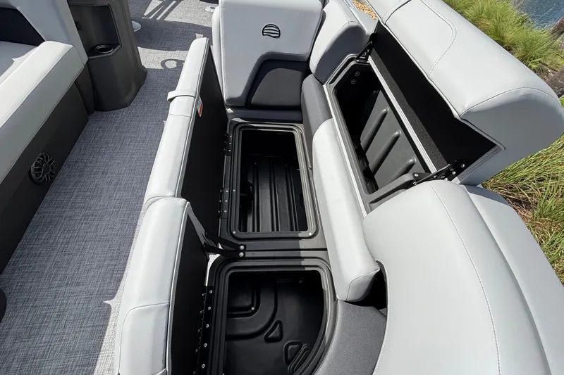 Slide: The Image of 2027 Sun Tracker Party Barge 20 DLX with open storage compartments and gray seating. - 13