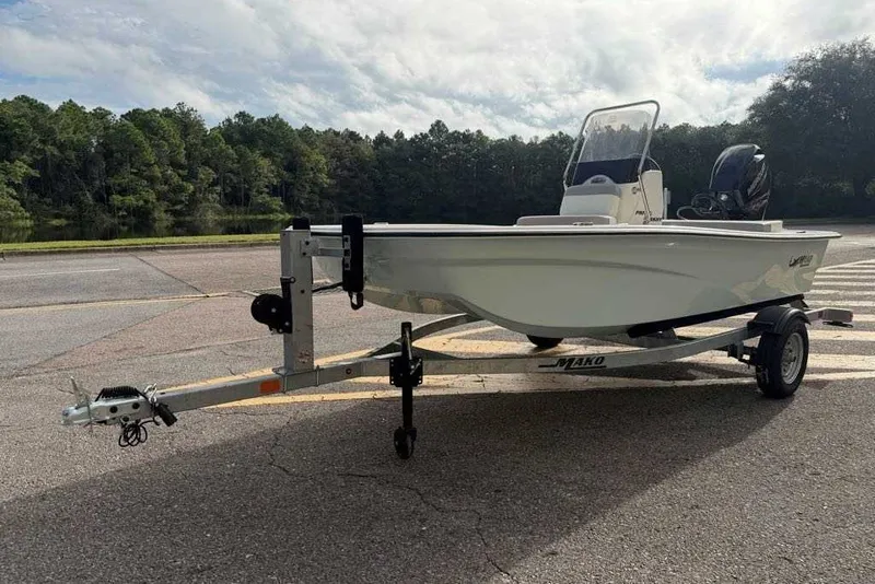 Slide: The Image of 2026 Mako Pro Skiff 13 CC boat on trailer, parked near a forested area. - 2