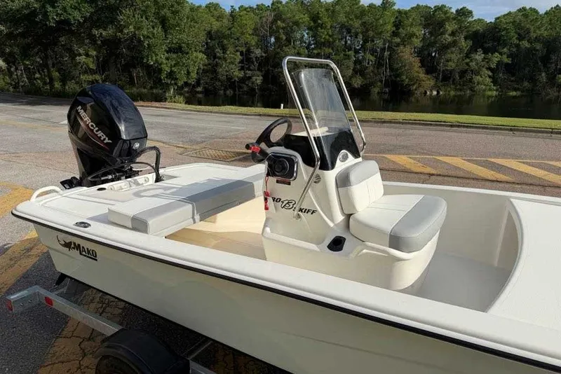 Slide: The Image of 2026 Mako Pro Skiff 13 CC boat with Mercury engine, parked near a lake. - 11