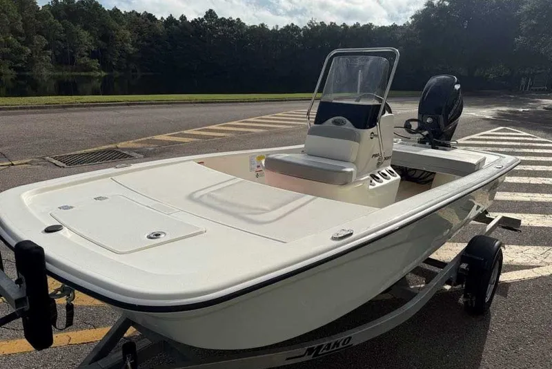 Slide: The Image of 2026 Mako Pro Skiff 13 CC boat on trailer, parked near a scenic lake. - 9