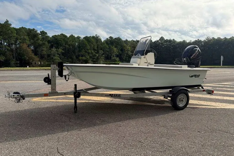 Slide: The Image of 2026 Mako Pro Skiff 13 CC boat on trailer, parked on road with forest background. - 3