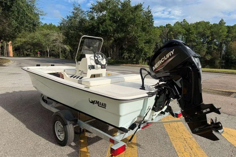 Slide: The Image of 2026 Mako Pro Skiff 13 CC boat with Mercury engine on trailer, parked outdoors. - 10