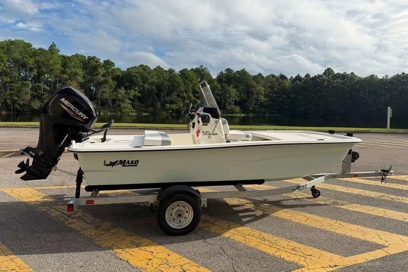Slide: The Image of 2026 Mako Pro Skiff 13 CC boat on trailer, parked near a lake. - 1