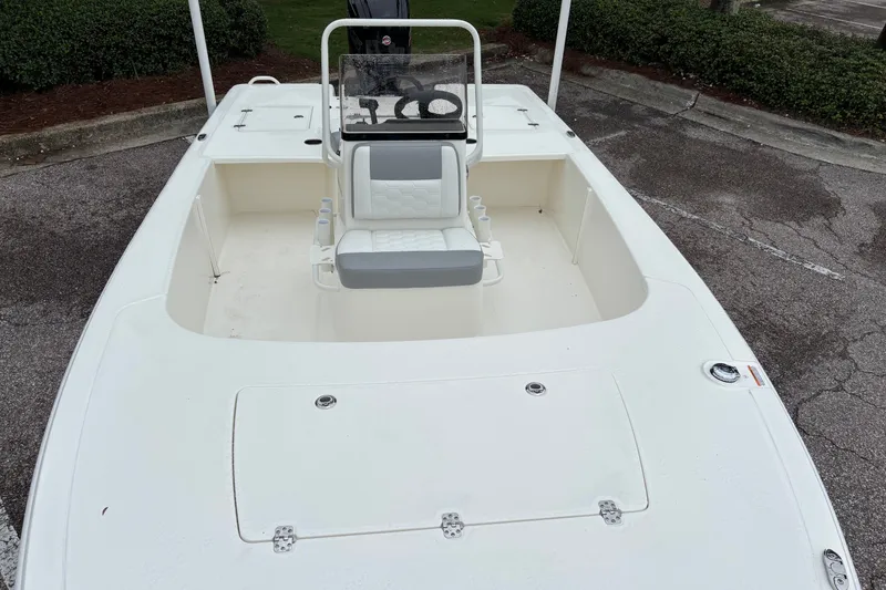 Slide: The Image of 2026 Mako 18 Pro Skiff boat with seating and storage, parked on pavement. - 8