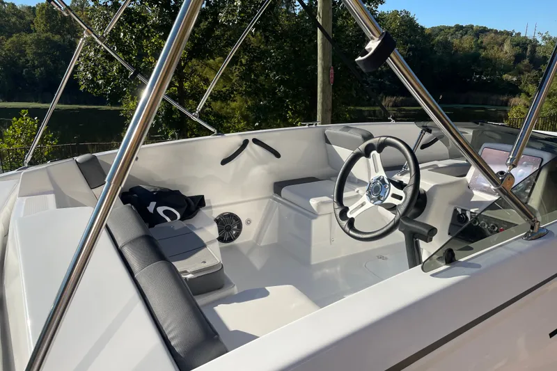 Slide: The Image of 2027 Tahoe T18 boat interior with steering wheel and seating, surrounded by lush greenery. - 6