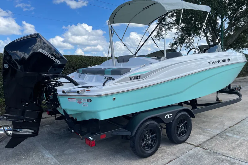 Slide: The Image of 2027 Tahoe T21 boat with Mercury engine on trailer, under clear blue sky. - 6