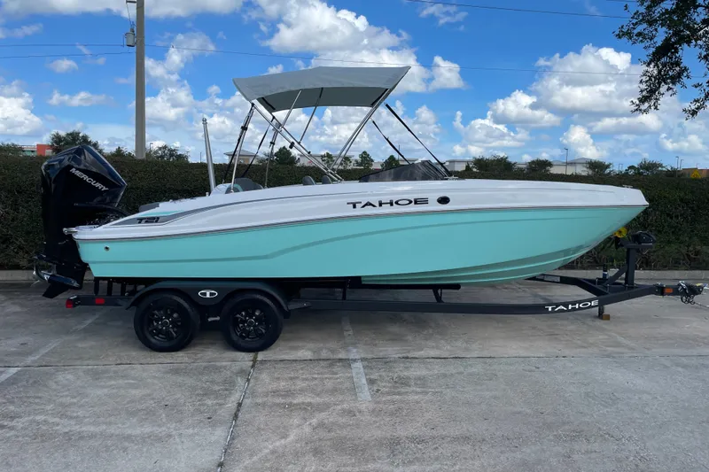 Slide: The Image of 2027 Tahoe T21 boat with canopy on trailer, parked outdoors under blue sky. - 4