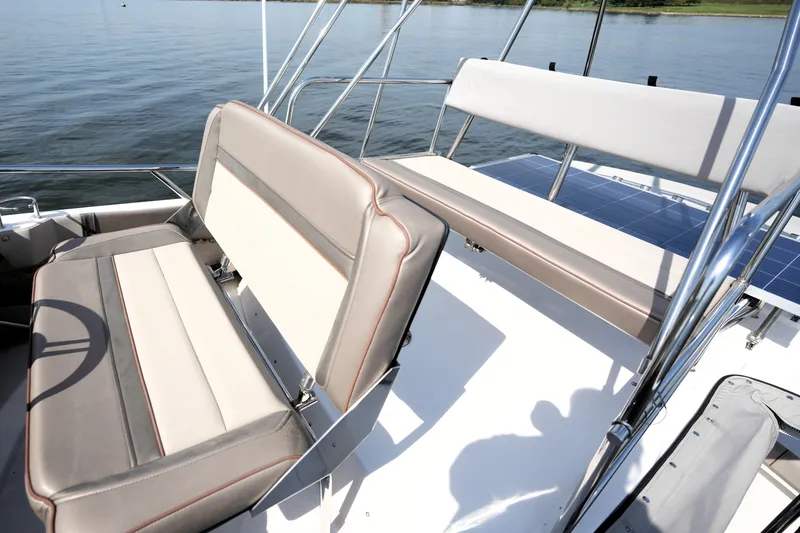 Slide: The Image of 2021 Cutwater C-32 CB boat interior with cushioned seating and railing, on calm water. - 26