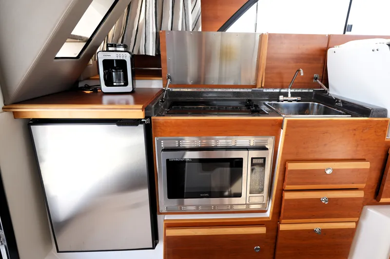 Slide: The Image of 2021 Cutwater C-32 CB boat kitchen with microwave, sink, and refrigerator. - 30