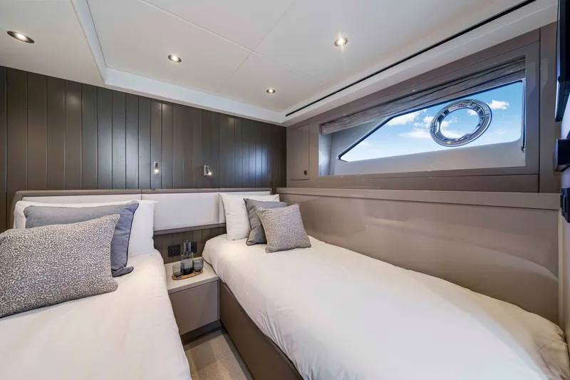 Slide: The Image of The 2027 Sunseeker Manhattan 68 cabin features twin beds, modern lighting, and a window. - 29