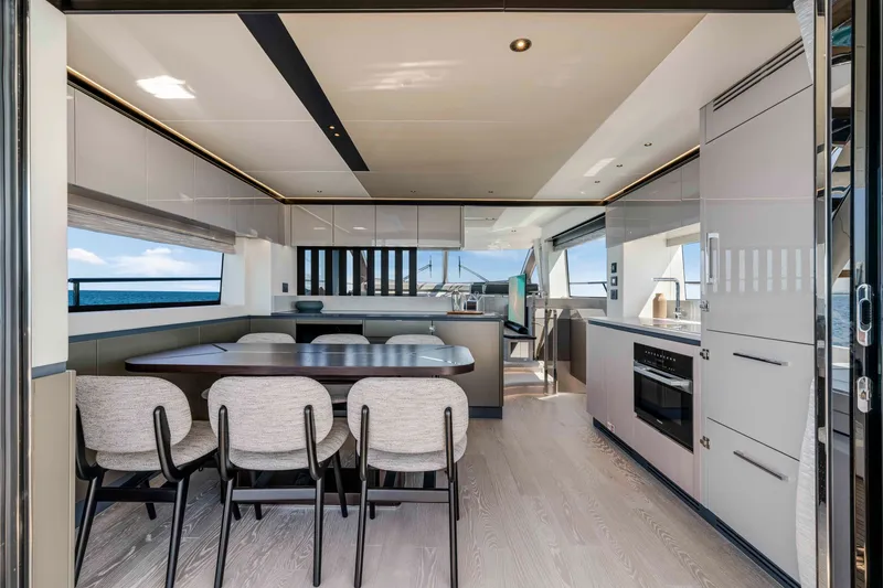 Slide: The Image of Interior view of a modern yacht with a stylish dining area and kitchen, surrounded by large windows. - 17