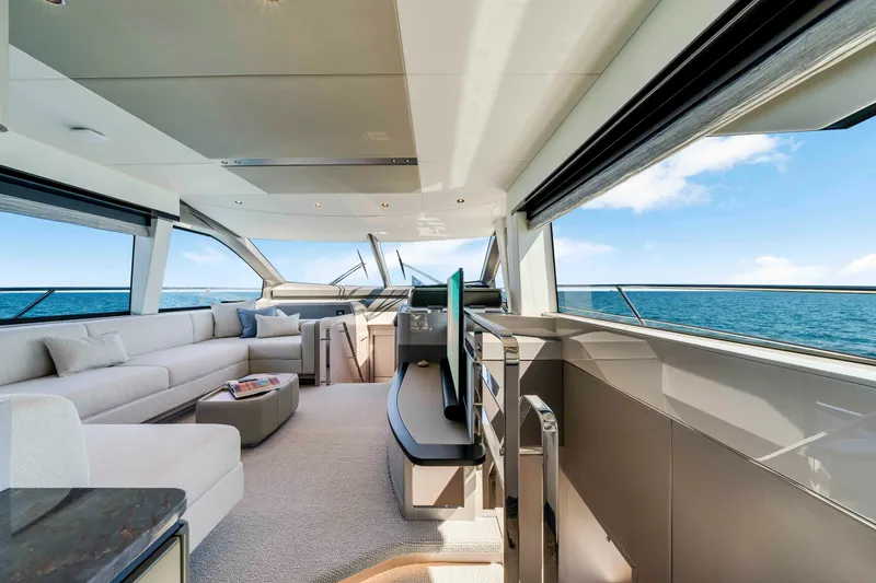 Slide: The Image of The image shows the luxurious interior of a Sunseeker Manhattan 68 yacht. There's an elegant seating area with a modern sofa and coffee table. Large windows offer stunning sea views. - 21