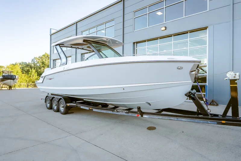 The Image of 2027 Monterey Elite 30 OB boat on trailer, parked outside modern building. - 0