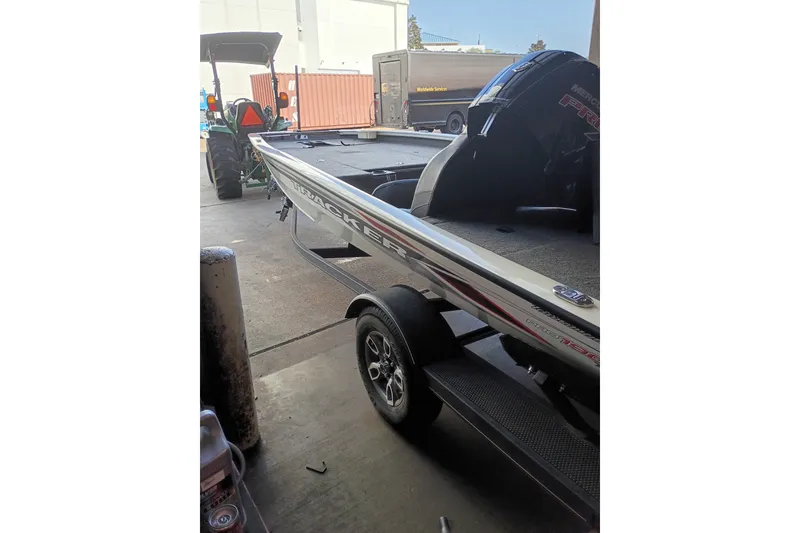 Slide: The Image of 2023 TRACKER PRO190 boat on trailer, parked in a garage with equipment nearby. - 13