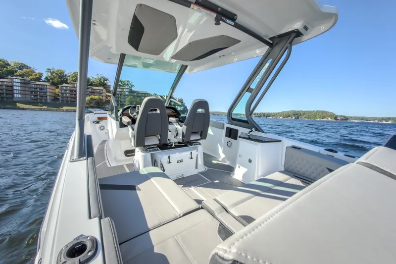 Slide: The Image of 2027 Monterey Elite 27 OB boat interior on a sunny lake, showcasing modern seating and design. - 21