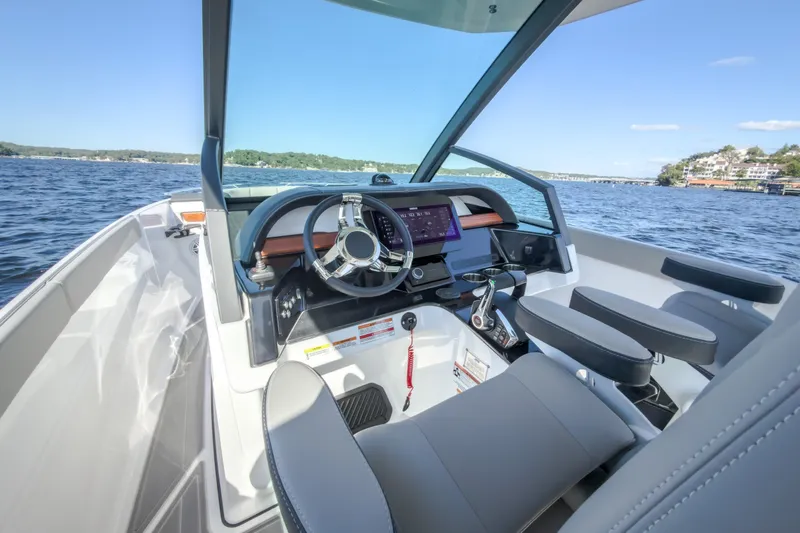 Slide: The Image of Cockpit of 2027 Monterey Elite 27 OB boat with modern steering and controls on a lake. - 79