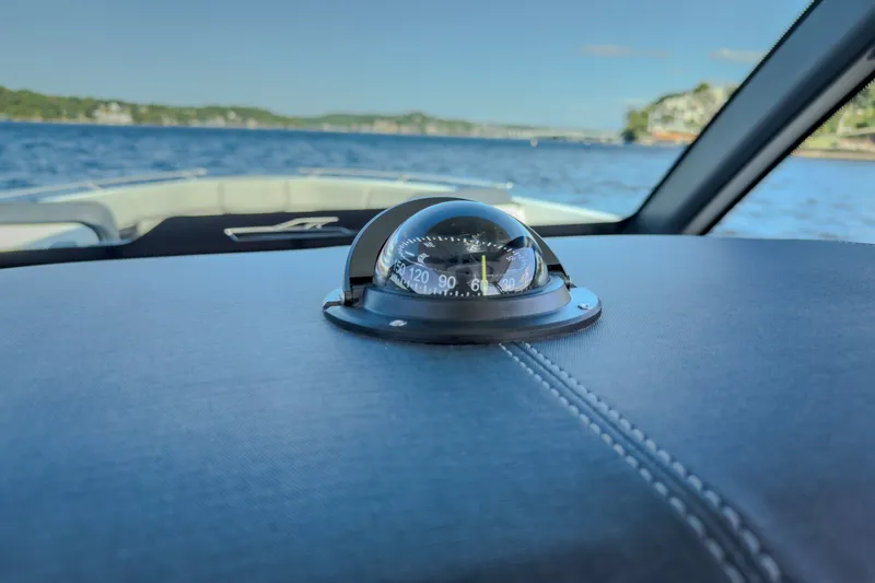 Slide: The Image of Compass on 2027 Monterey Elite 27 OB boat dashboard with scenic water view. - 73
