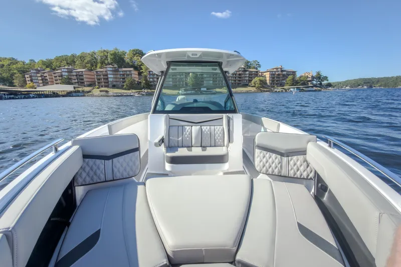 Slide: The Image of 2027 Monterey Elite 27 OB boat interior with luxurious seating on a scenic lake. - 61