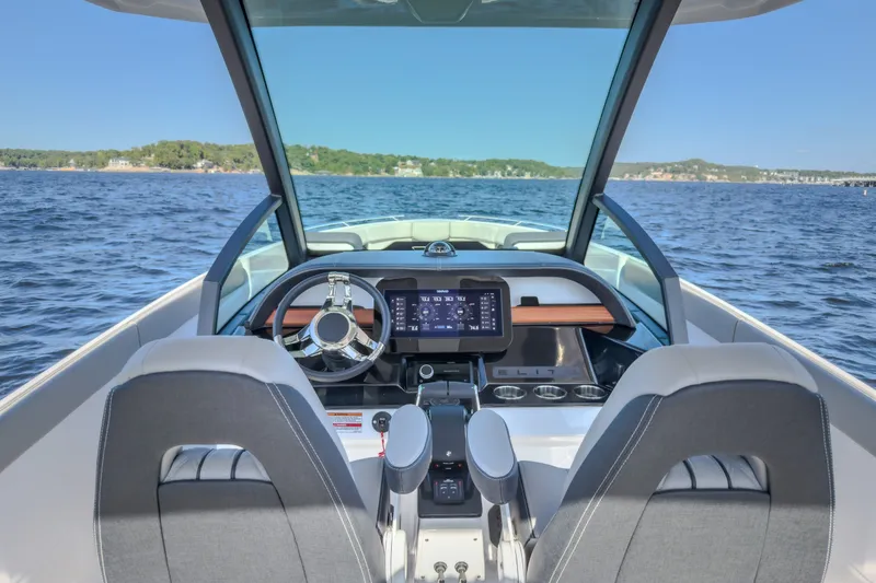 Slide: The Image of Cockpit view of 2027 Monterey Elite 27 OB boat on a serene lake. - 76