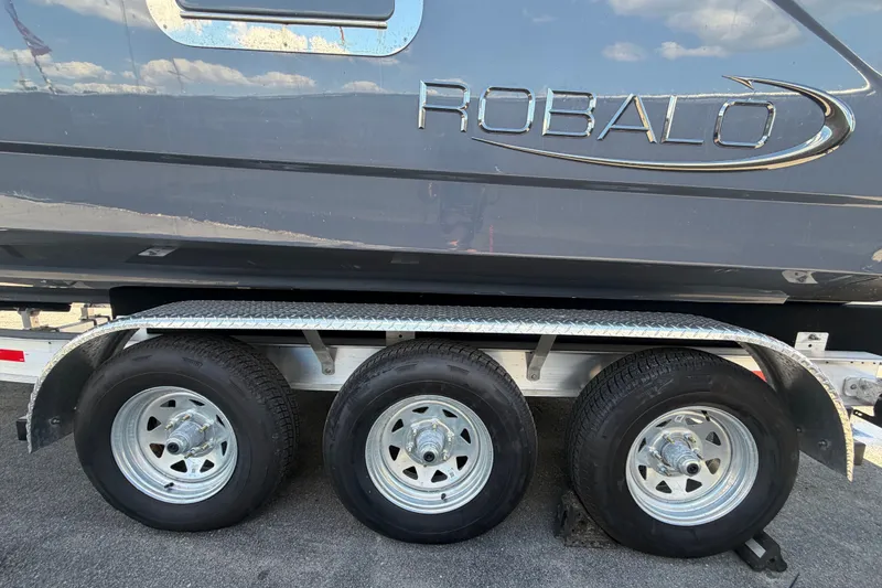 Slide: The Image of 2025 Robalo R302 Center Console boat on a triple-axle trailer. - 93