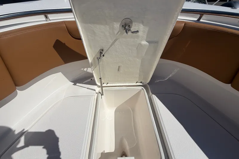 Slide: The Image of 2025 Robalo R302 Center Console boat storage compartment with open hatch and seating area. - 47