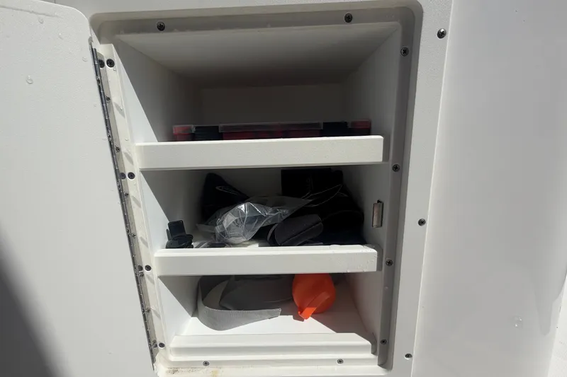 Slide: The Image of Storage compartment in 2025 Robalo R302 Center Console boat, featuring shelves with various items. - 40
