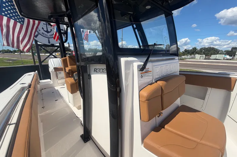 Slide: The Image of 2025 Robalo R302 Center Console boat with tan seating and American flags. - 69