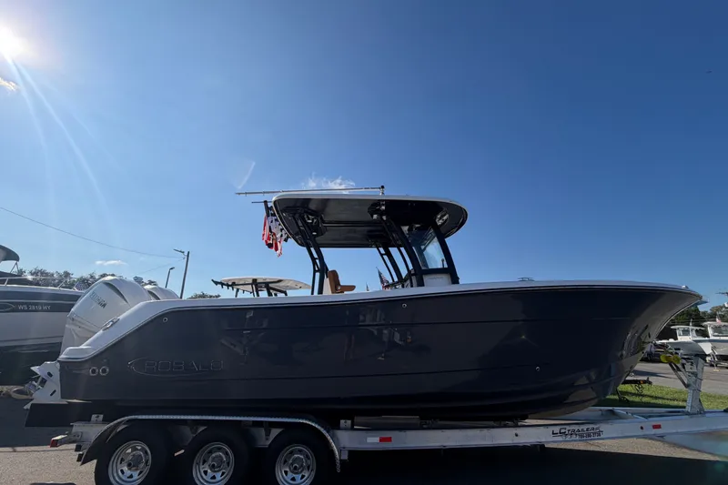 The Image of 2025 Robalo R302 Center Console boat on trailer under clear blue sky. - 0