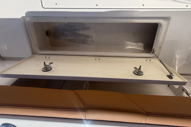 Slide: The Image of 2025 Robalo R302 Center Console storage compartment with open hatch and cushioned seating. - 76