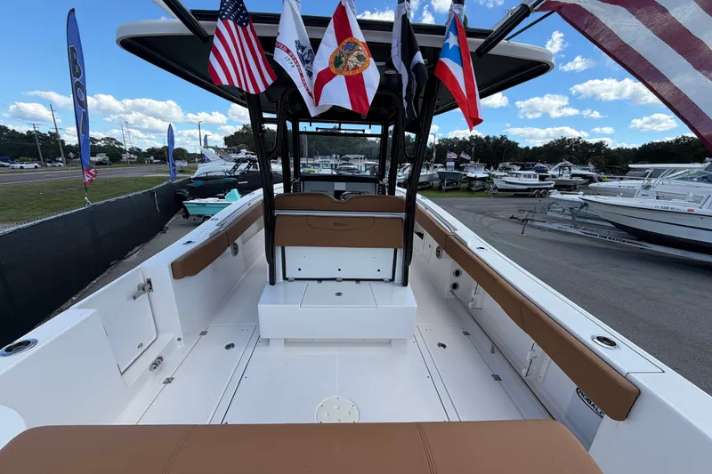 Slide: The Image of 2025 Robalo R302 Center Console boat with flags, docked at a marina under a blue sky. - 15