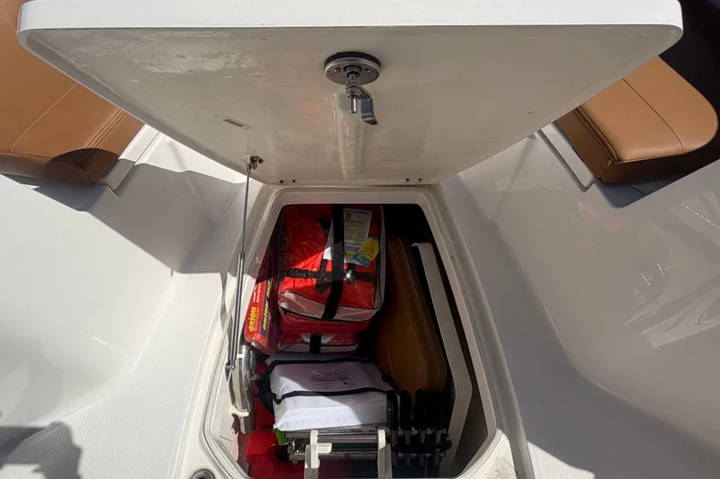 Slide: The Image of Open storage compartment on 2025 Robalo R302 Center Console boat, containing safety equipment. - 52