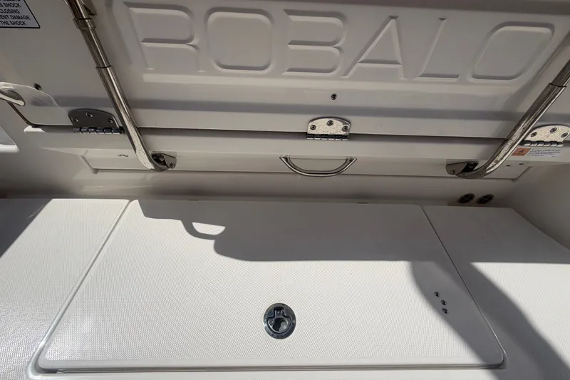 Slide: The Image of 2025 Robalo R302 Center Console boat storage compartment with stainless steel hinges and handle. - 80