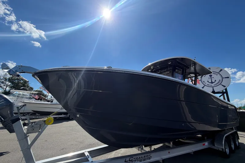 Slide: The Image of 2025 Robalo R302 Center Console boat on trailer under bright blue sky. - 12