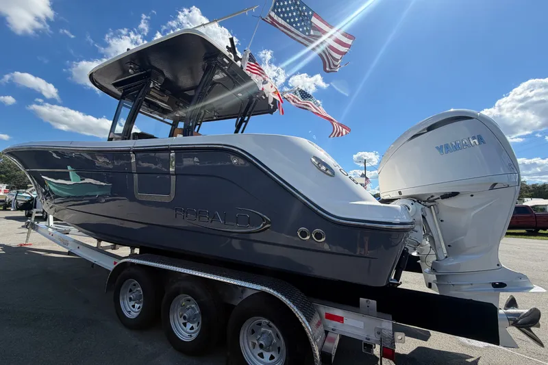 Slide: The Image of 2025 Robalo R302 Center Console boat on trailer, featuring Yamaha engine, under clear blue sky. - 10