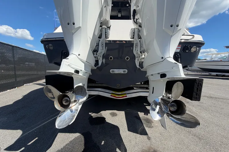 Slide: The Image of 2025 Robalo R302 Center Console boat with dual outboard engines, docked under a clear sky. - 5