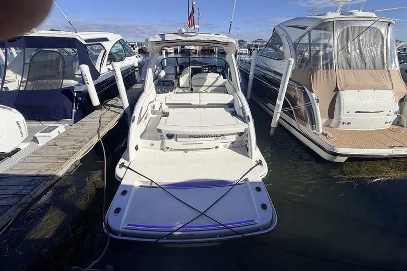 Slide: The Image of 2023 Formula 350 Crossover Bowrider I/O docked among other boats at a marina. - 2