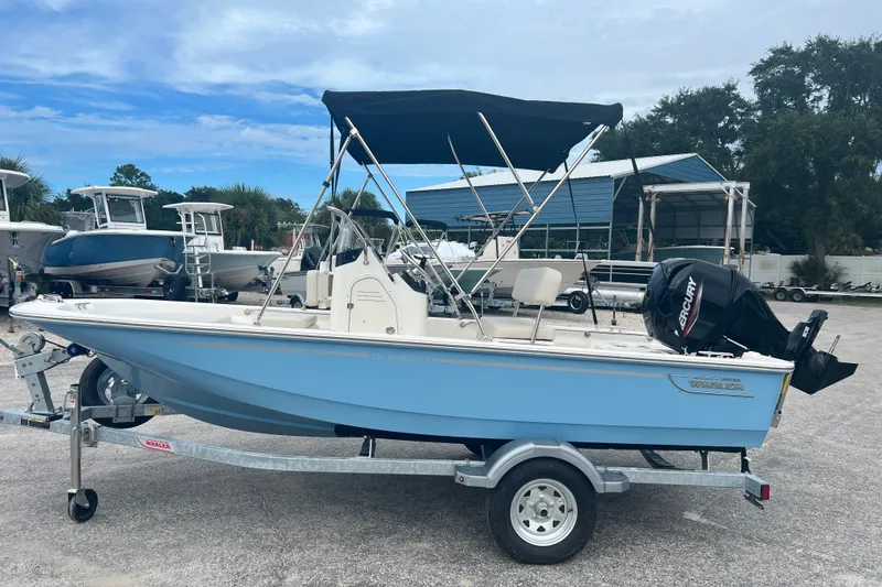 Slide: The Image of 2027 Boston Whaler 150 Montauk boat with canopy on trailer, parked outdoors. - 5