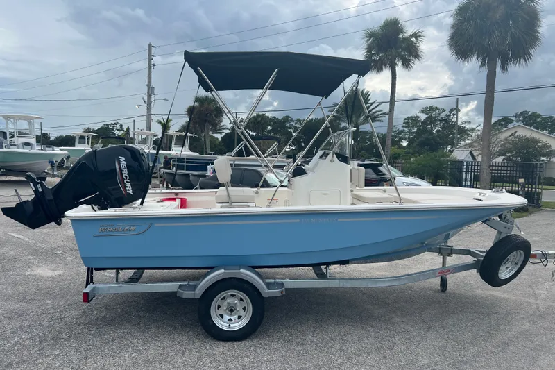 The Image of 2027 Boston Whaler 150 Montauk boat on trailer, featuring a Mercury outboard motor. - 0