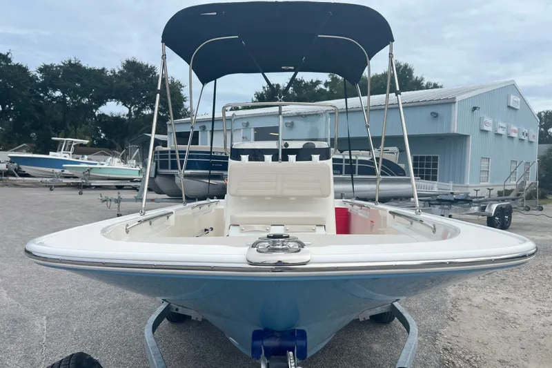 Slide: The Image of 2027 Boston Whaler 150 Montauk boat with canopy, parked outdoors near a blue building. - 3