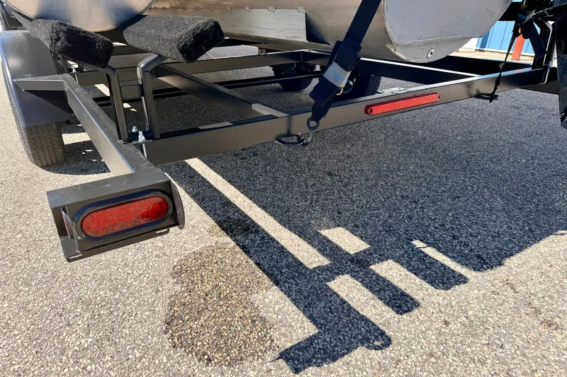 Slide: The Image of Trailer of 2021 Manitou 23 Oasis boat on asphalt, showing rear light and frame. - 95